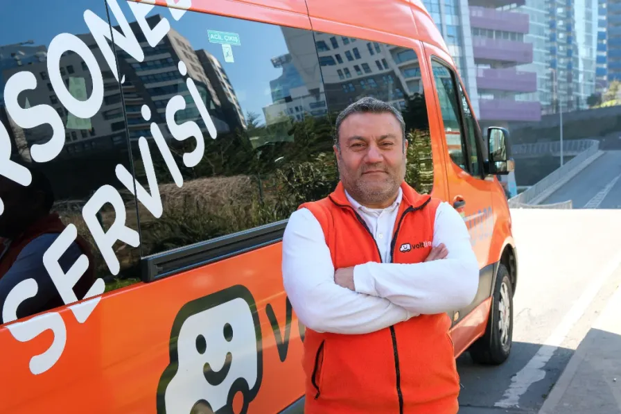 A Volt Lines driver in an orange vest standing beside the shuttle