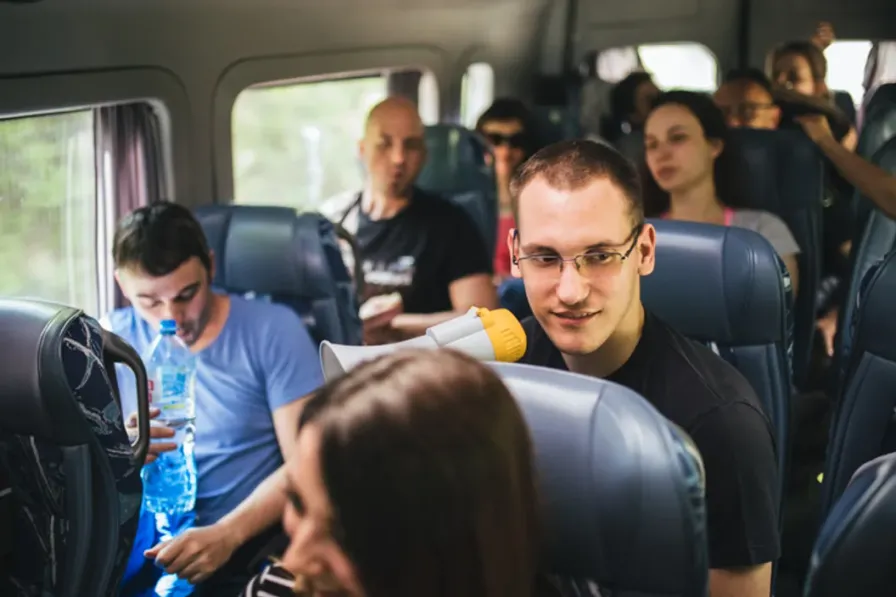 A shift crew filling a shuttle, talking across the seats and settling in for the ride